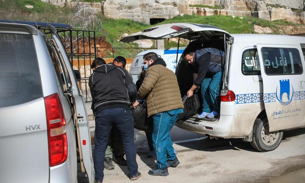 أشخاص ينقلون جثامين لضحايا جراء الزلزال دخلت من تركيا إلى الشمال السوري عبر معبر "باب الهوى" الحدودي - 7 شباط 2023 (معبر "باب الهوى" / فيس بوك)