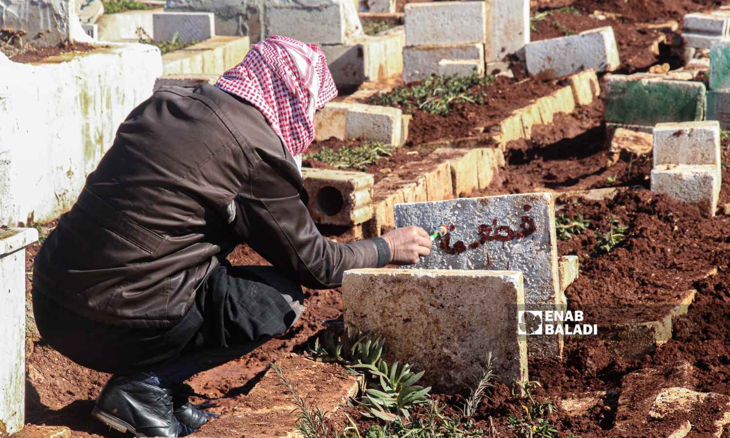 رجل يكتب اسمًا على شاهدة قبر أحد ضحايا الزلزال الذي ضرب مناطق شمال غربي سوريا في بلدة حربنوش بريف إدلب - 8 شباط 2023 ( إياد عبد الجواد /عنب بلدي)