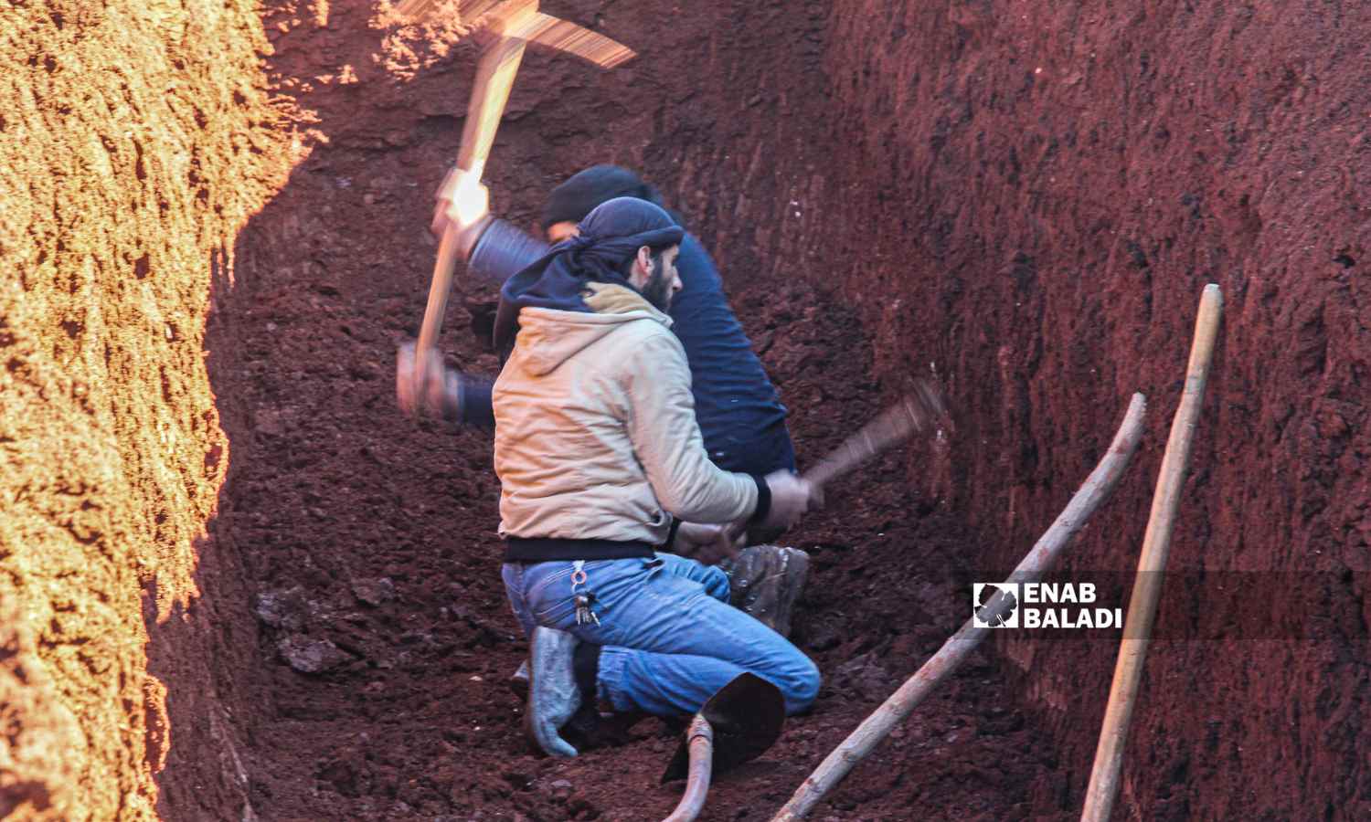 رجلان يحفران قبرًا جماعيًا في بلدة حربنوش لدفن ضحايا البلدة إثر زلزال ضرب مناطق شمال غربي سوريا - 8 شباط 2023 (إياد عبد الجواد /عنب بلدي)