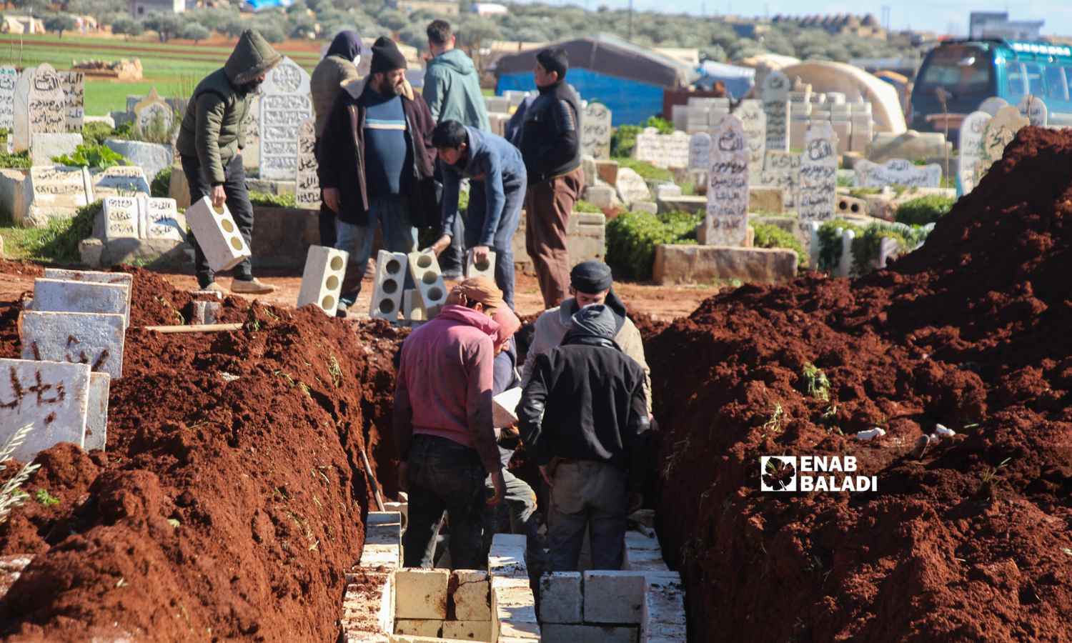 رجال يحملون أحجارًا إسمنتية لصنع مقبرة جماعية في بلدة حربنوش لدفن ضحايا البلدة إثر زلزال ضرب مناطق شمال غربي سوريا - 8 شباط 2023 (إياد عبد الجواد /عنب بلدي)
