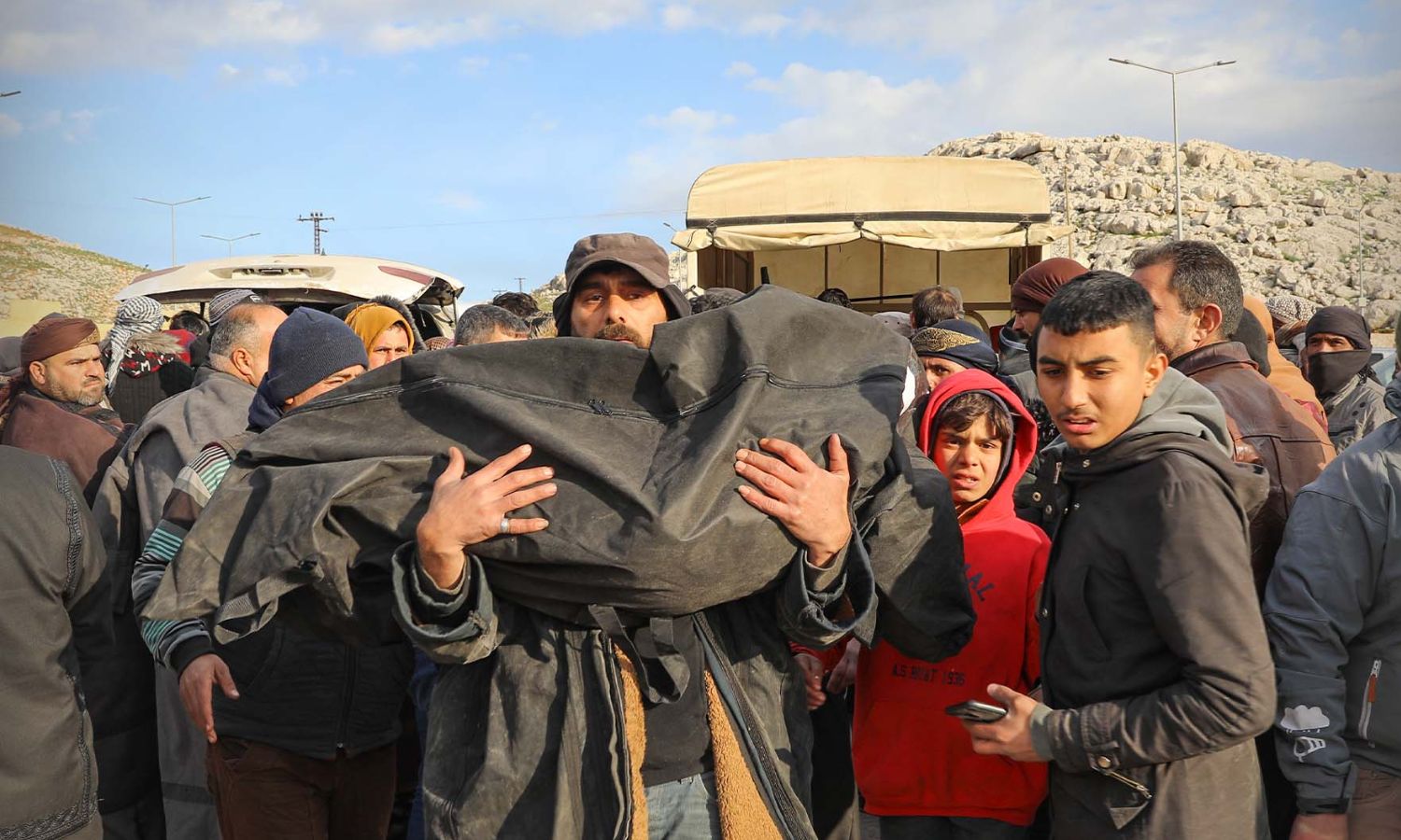 رجل يحمل جثمان لضحية جراء الزلزال وصلت من تركيا إلى الشمال السوري- 7 شباط 2023 (معبر باب الهوى)