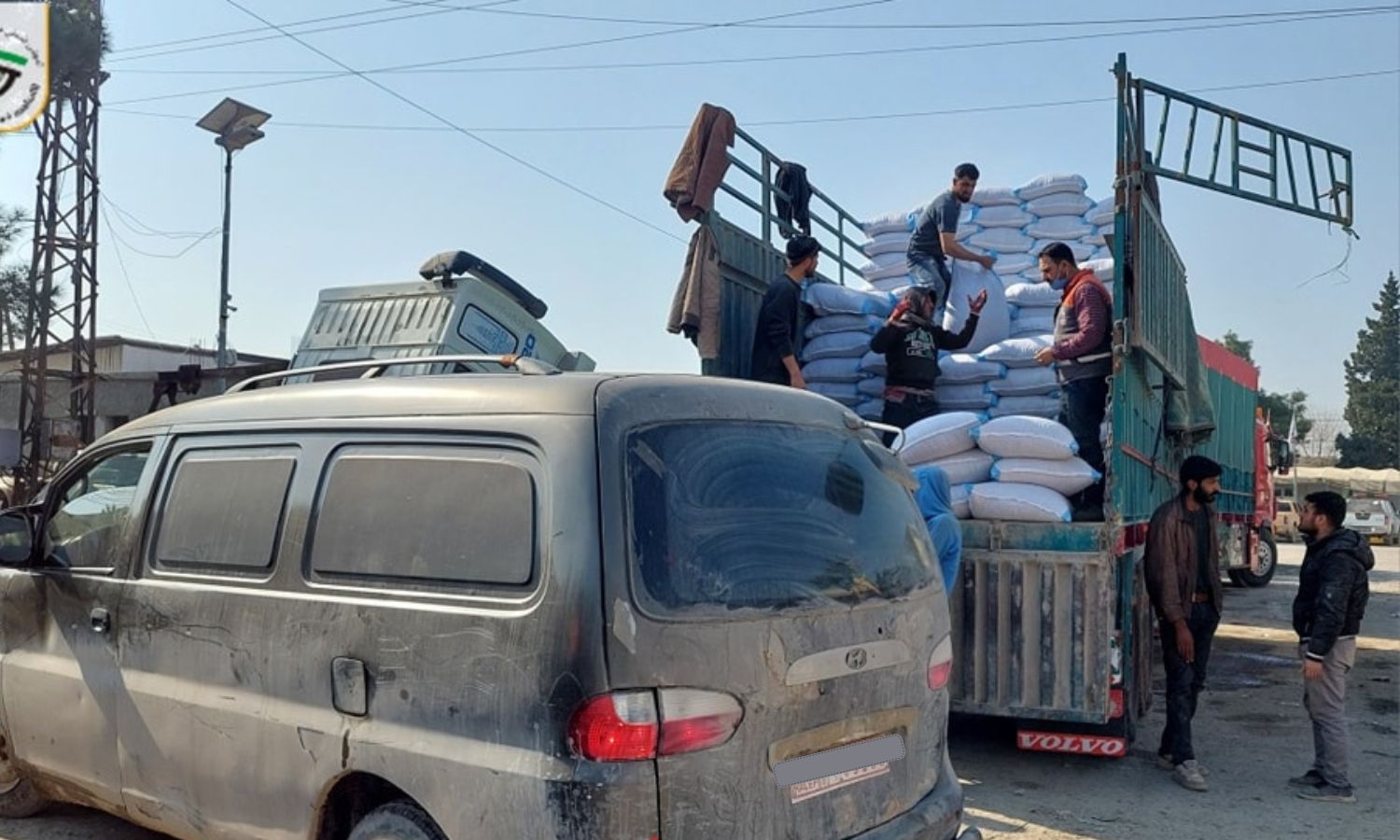 عمال ينقلون أعلاف للثروة الحيوانية من شاحنة في مدينة جرابلس بريف حلب الشمالي- 27 من كانون الثاني 2023 (محلي جرابلس/ فيس بوك)