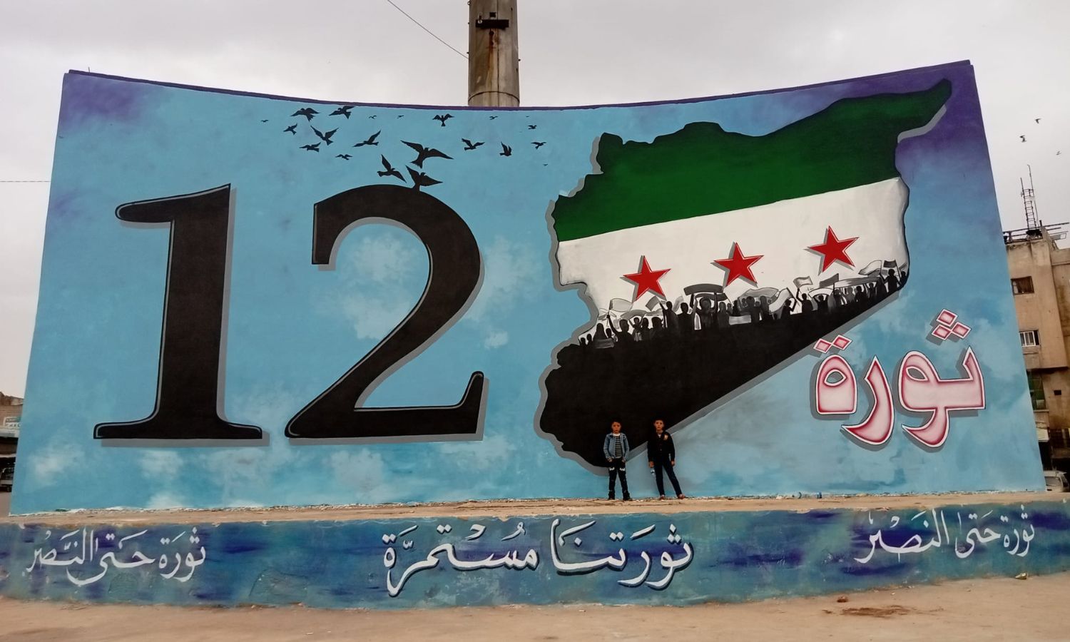 رسمة جدارية لفريق "ريشة أمل" على دوار "المحراب" في مدينة إدلب في الذكرى الـ12 للثورة السورية- 14 من آذار 2023 (Nouri Al-rawwal/ فيس بوك)