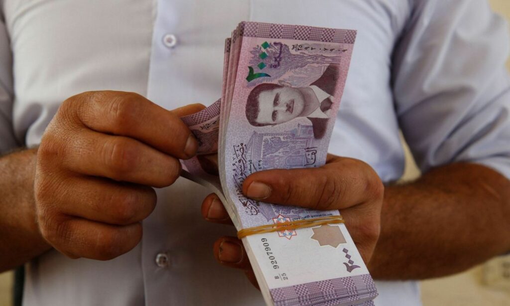رجل يعد أوراق نقدية من فئة ألفي ليرة سورية (تشرين)