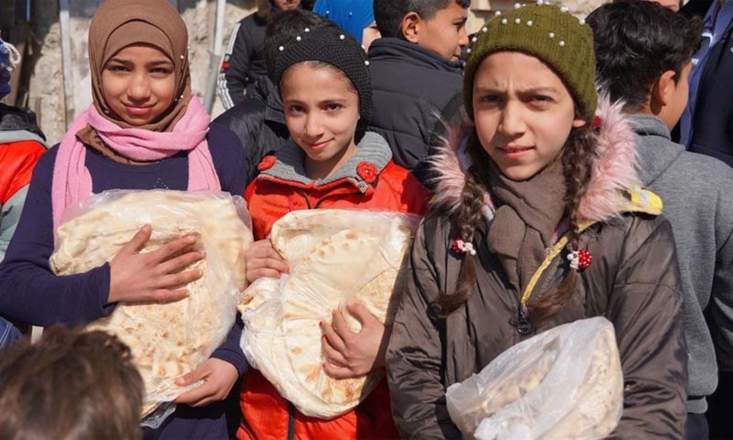 طفلات يحملن ربطات خبز حصلن عليها من أحد المخابز في حلب، حيث يساعد برنامج الأغذية العالمي في توزيع الطعام (WFP)