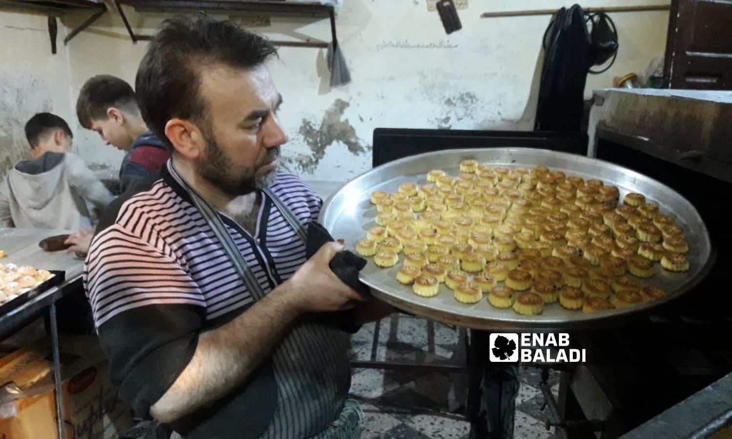 رجل يحضر "معمول" العيد في أحد الأفران بمدينة إدلب شمالي سوريا- 20 من نيسان 2023 (عنب بلدي/ أنس الخولي)