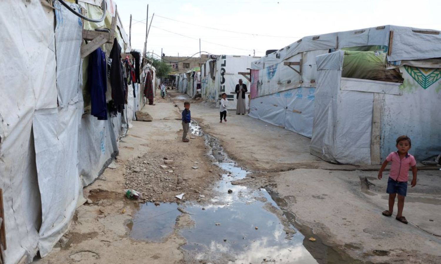 أطفال سوريون لاجئون يقفون قرب مجرى المياه في مخيم بسهل البقاع اللبناني- 18 من تشرين الأول 2022 (رويترز)