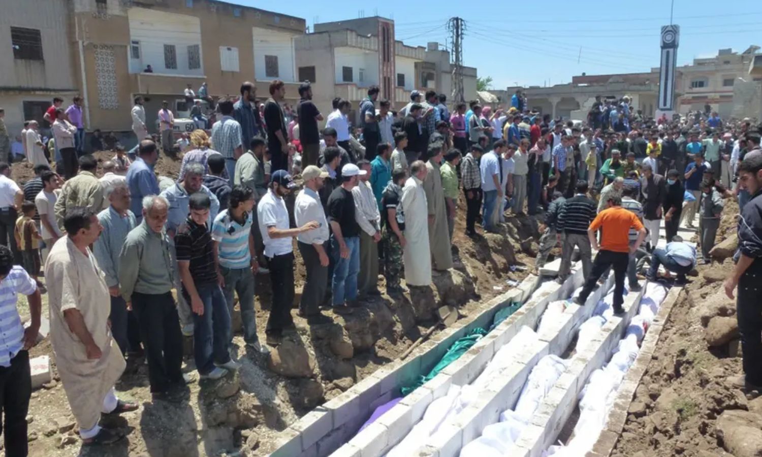 أشخاص يحتشدون حول مقابر جماعية لدفن قتلى مجزرة الحولة- 26 من أيار 2012 (AFP)