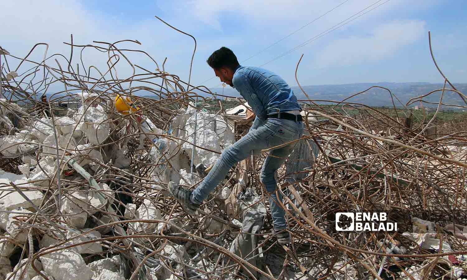 عمال يقومون باستخراج قضبان الحديد من الأبنية المدمرة بفعل الزلزال في سلقين بريف إدلب- 30 نيسان 2023(عنب بلدي- إياد عبد الجواد)