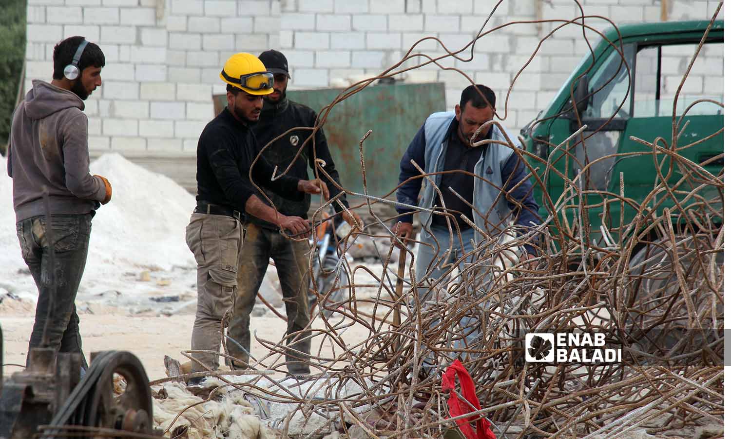 عمال يقومون باستخراج قضبان الحديد من الأبنية المدمرة بفعل الزلزال في سلقين بريف إدلب- 30 نيسان 2023(عنب بلدي- إياد عبد الجواد)