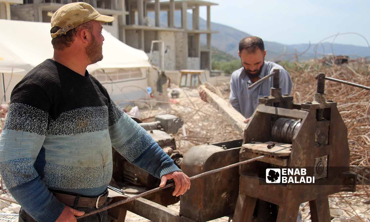 عمال يقومون بمعالجة قضبان الحديد المستخرجة من ركام الأبنية المدمرة بفعل الزلزال لإعادة تدويرها واستخدامها في سلقين بريف إدلب- 30 نيسان 2023(عنب بلدي- إياد عبد الجواد)