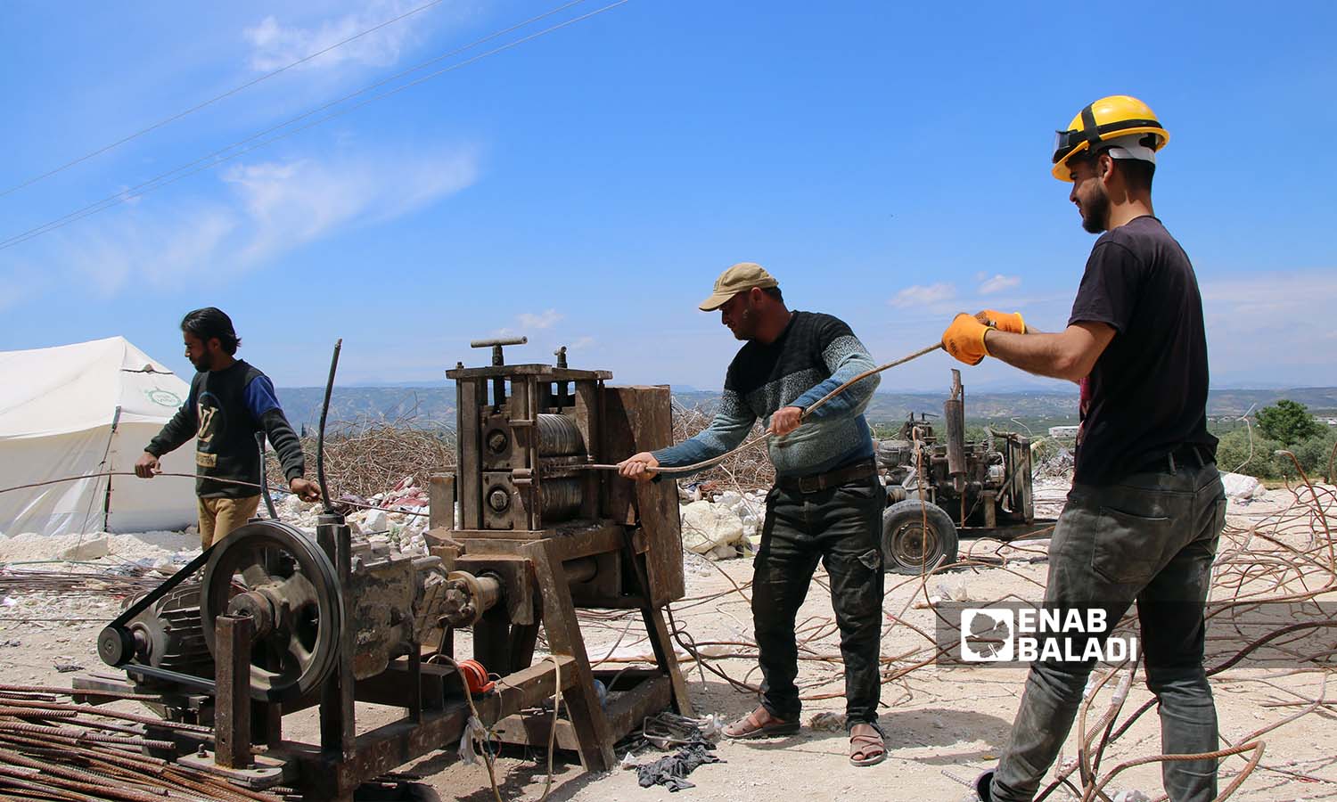 عمال يقومون بمعالجة قضبان الحديد المستخرجة من ركام الأبنية المدمرة بفعل الزلزال لإعادة تدويرها واستخدامها في سلقين بريف إدلب- 30 نيسان 2023(عنب بلدي- إياد عبد الجواد)