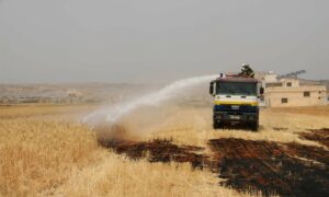 فرق الإطفاء في "الدفاع المدني السوري" تخمد حريقًا اندلع في الأراضي الزراعية شمال غربي سوريا- 22 من أيار 2023 (الدفاع المدني السوري/ فيس بوك)