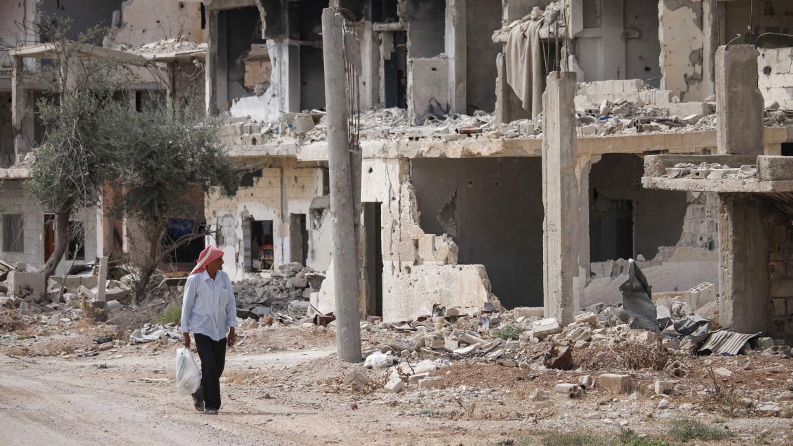 رجل سوري يمر من أمام أنقاض أبنية مدمرة في حي تسيطر عليه فصائل المعارضة بمدينة درعا جنوبي سوريا- 2 من تشرين الأول 2018 (AFP\ محمد أبازيد)