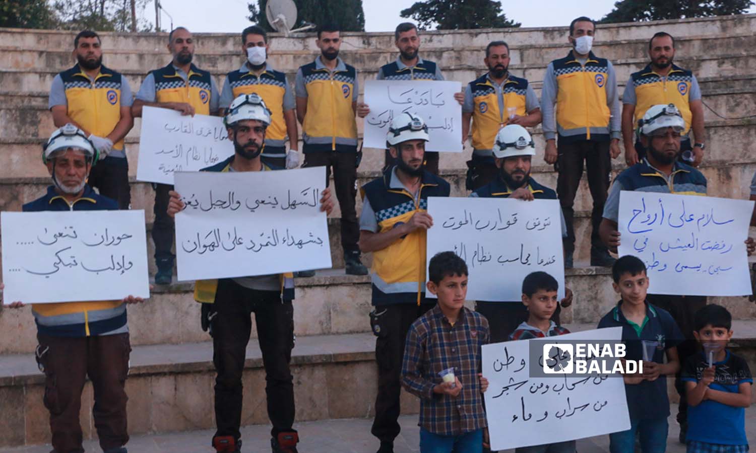  متطوعو الدفاع المدني السوري في مدينة إدلب يرفعون لافتات للمطالبة بفتح تحقيق بأسباب غرق قارب للاجئين على سواحل اليونان- 18 حزيران 2023 (عنب بلدي- أنس الخولي)