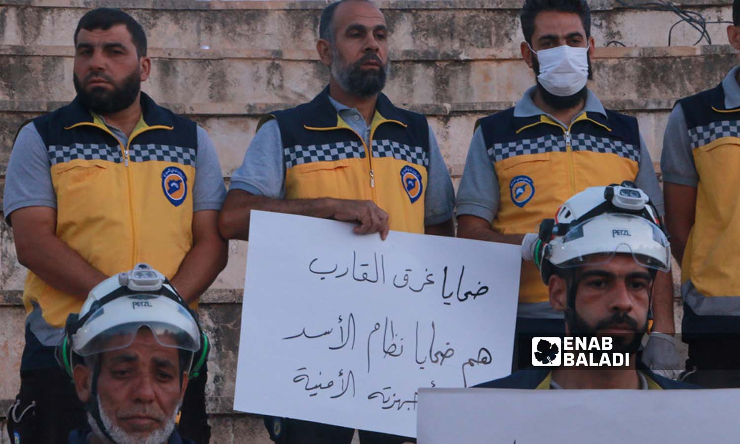  متطوعو الدفاع المدني السوري في مدينة إدلب يرفعون لافتات للمطالبة بفتح تحقيق بأسباب غرق قارب للاجئين على سواحل اليونان- 18 حزيران 2023 (عنب بلدي- أنس الخولي)
