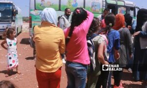 تلاميذ يصطفون بجانب باص تحول إلى فصل دراسي متنقل للأطفال الذين لم يذهبوا إلى المدرسة في مخيم للنازحين في مدينة جنديريس (عنب بلدي)