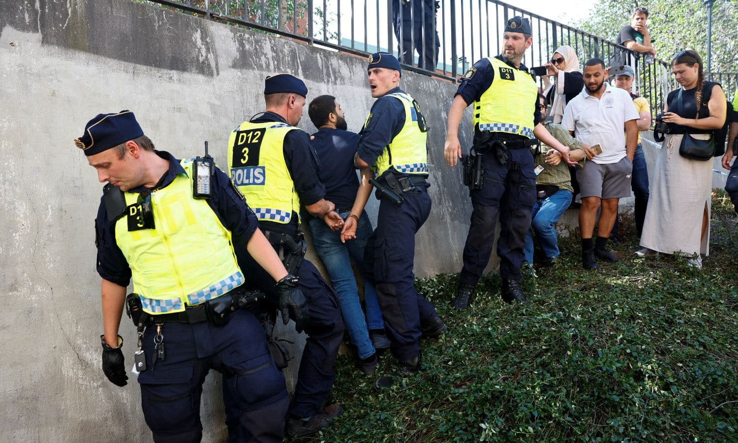 أشخاص يحاولون منع إحراق القرآن الكريم في السويد فيعتقلهم عناصر من الشرطة- 28 من حزيران 2023 (رويتزر)