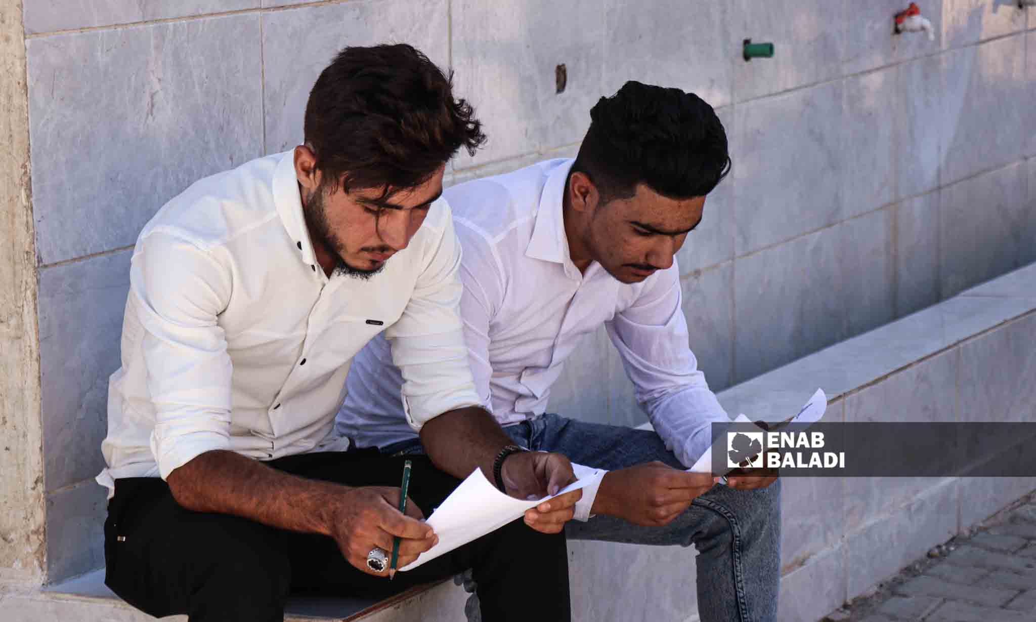 طالبان يراجعان معلوماتهم قبل الدخول لقاعة الامتحان  - 5 من تموز 2023 (عنب بلدي/ حسين شعبو)