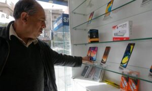 رجل يتفحص الهواتف المحمولة الذكية في محل هواتف بالعاصمة السورية - 24 آذار 2021 (AFP)