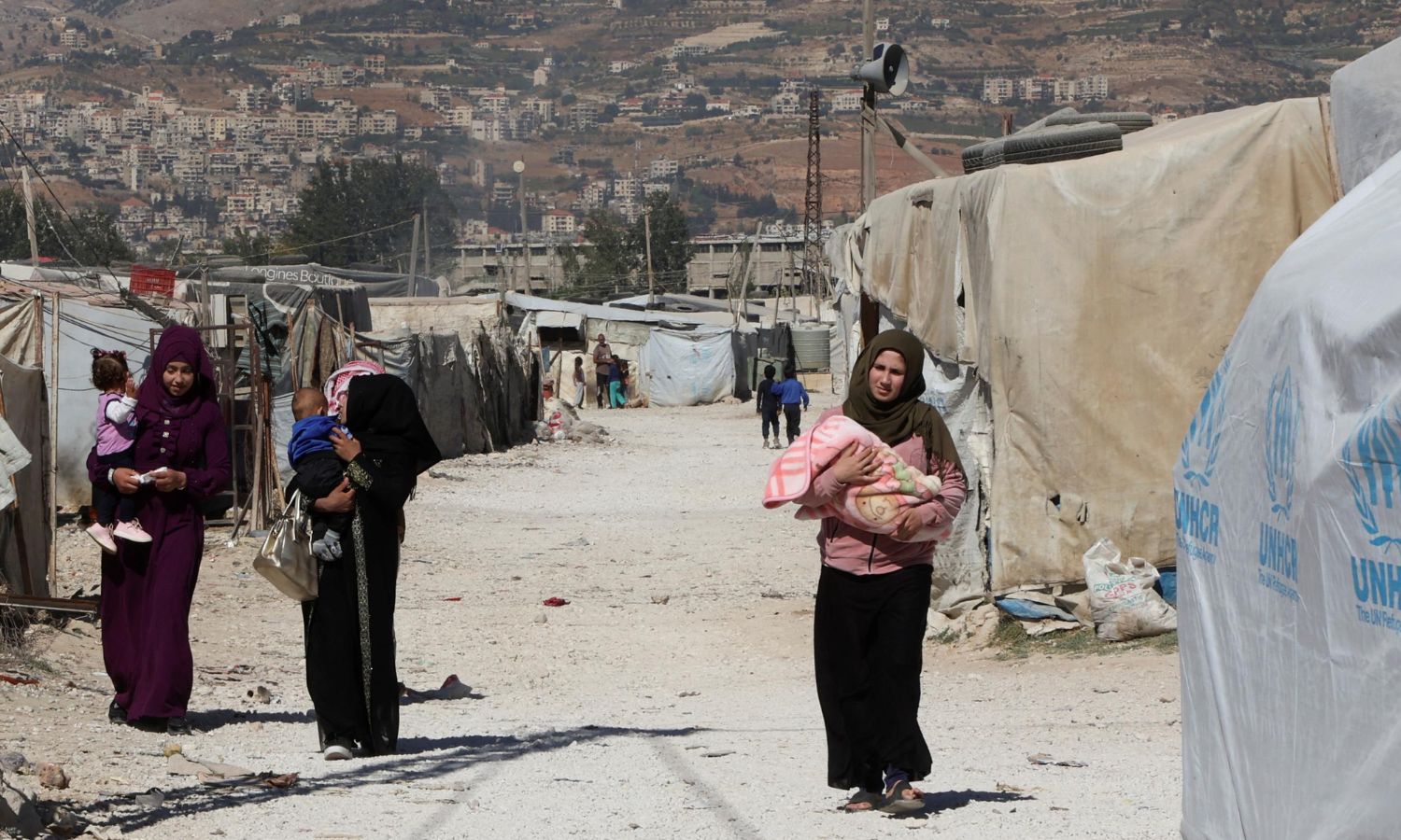 لاجئات سوريات يحملن أطفالهن في مخيم غير رسمي في وادي البقاع بلبنان- 18 من تشريين الأول 2022 (رويترز)