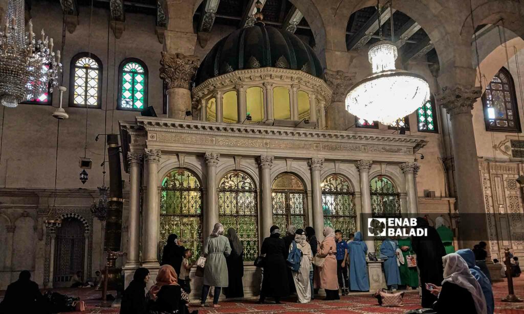 رجال ونساء يقفون أمام مقام النبي يحيى في المسجد الأموي بدمشق من الداخل - 26 من تموز 2023 (عنب بلدي/سارة الأحمد)