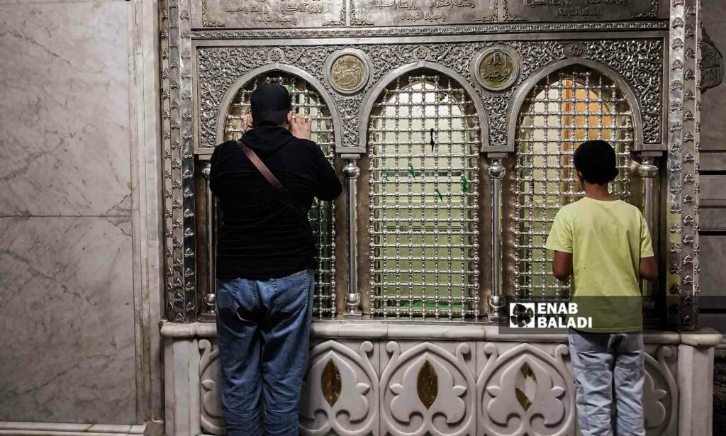 رجل وطفل يقفان أمام مقام النبي يحيى في المسجد الأموي بدمشق من الداخل - 26 من تموز 2023 (عنب بلدي/سارة الأحمد)