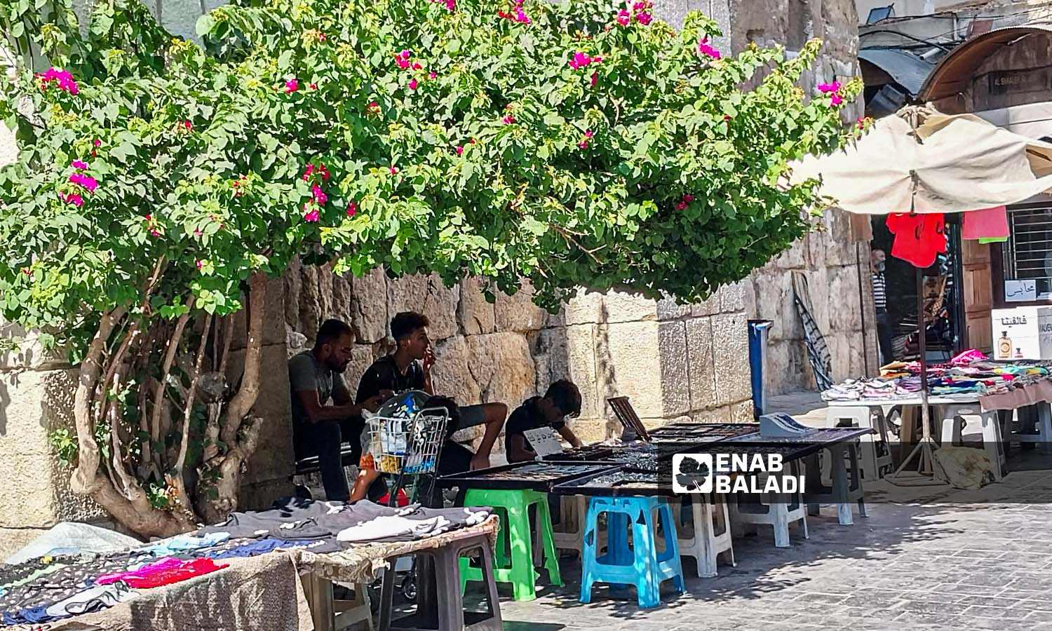 شباب يجلسون أمام بسطات لبيع التحف والتذاكر  بحي القيمرية في دمشق - 26 من تموز 2023 (عنب بلدي / سارة الأحمد)
