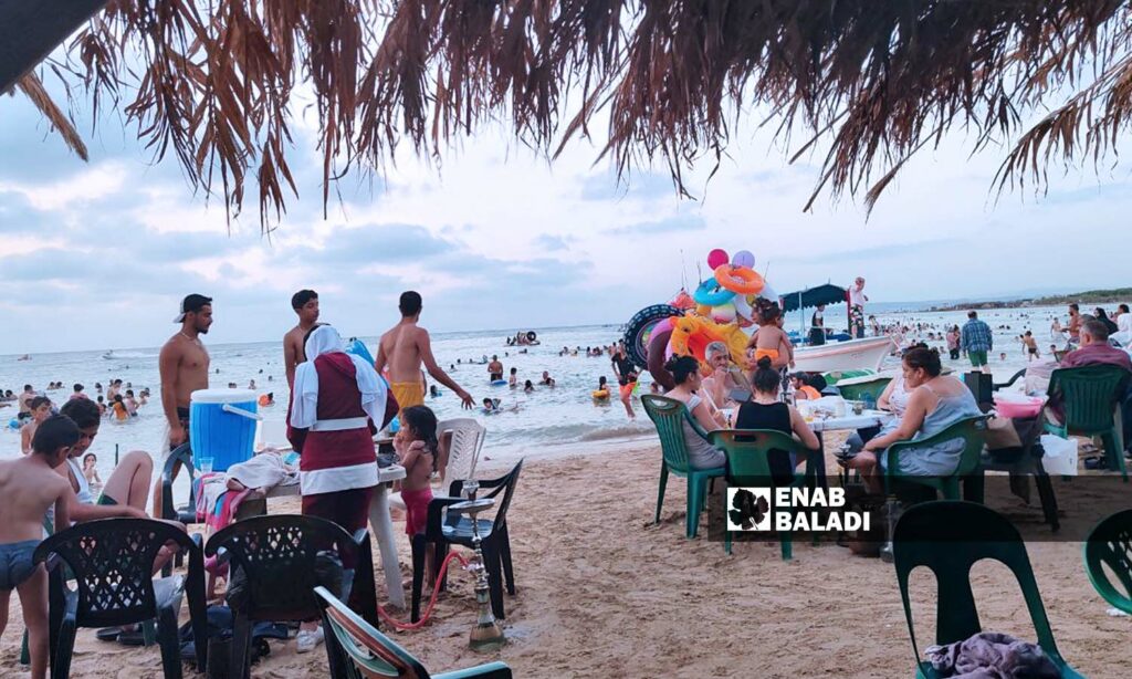 يقدم شاطئ "الكرنك" خدمات أرخص قياسًا بالمنتجعات، لكنه لايزال خارج قدرة غالبية أهالي مدينة اللاذقية - 12 من آب 2023 (عنب بلدي/ليندا علي)