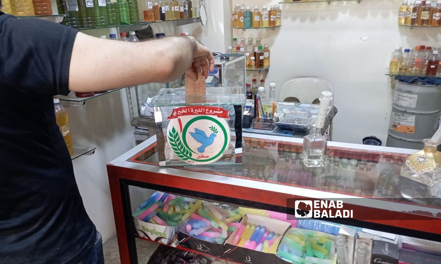 صندوق لجمع التبرعات داخل محل عطورات في سلقين شمالي إدلب- 21 من آب 2023 (عنب بلدي)