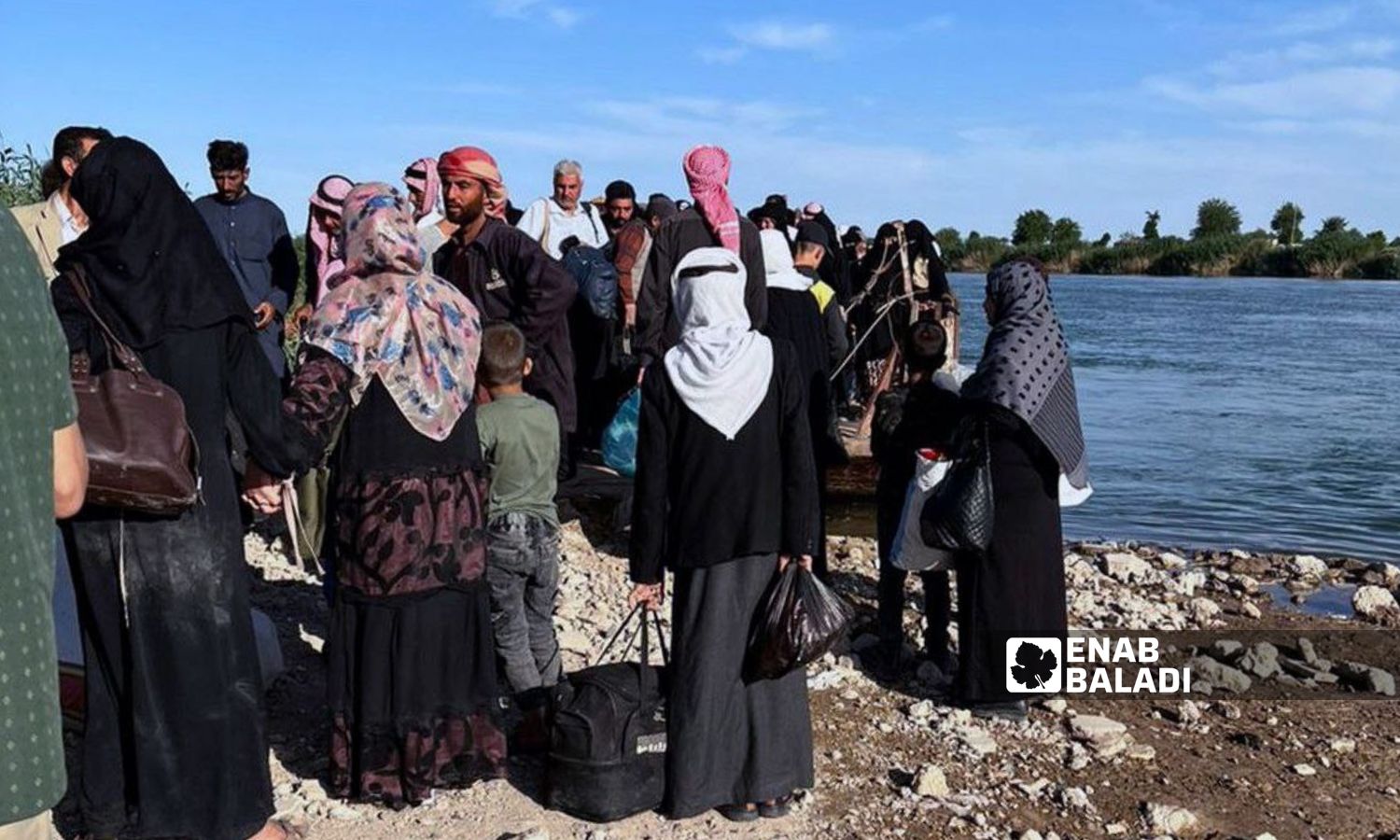 مدنيون ينتظرون على ضفة نهر الفرات للعبور نحو مناطق سيطرة النظام السوري من جهة مدينة الميادين شرقي دير الزور- 14 من حزيران 2023 (عنب بلدي)