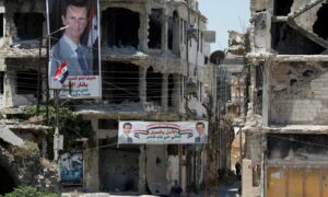 لافتتا داعية لانتخاب الأسد علقت على المباني المدمرة في حمص (رويترز)
