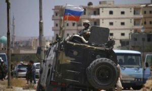 جندي روسي على عربته المدرعة يراقب المعارضين لاتفاق "التسوية" في أثناء إجلائهم من مدينة درعا- 15 من تموز 2018 (AFP)