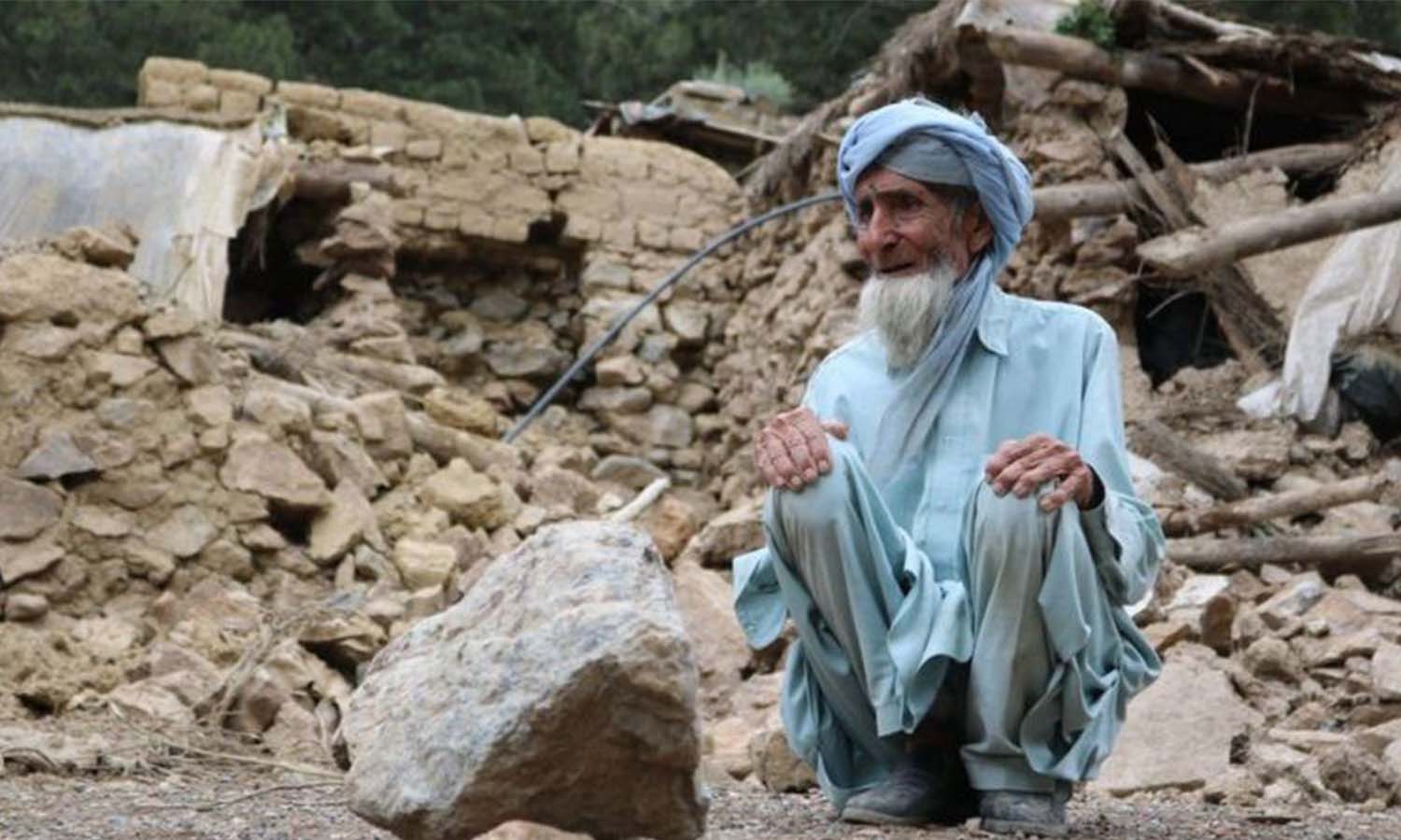 رجل أفغاني يجلس بالقرب من منزله الذي دمره الزلزال في أفغانستان - 22 حزيران 2022-(Getty images)