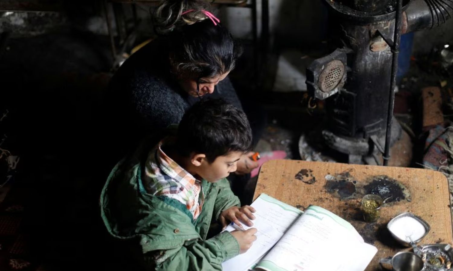 امرأة تساعد أطفالها في الدراسة خلال الشتاء في دمشق- 30 من تشرين الثاني 2022 (رويترز)