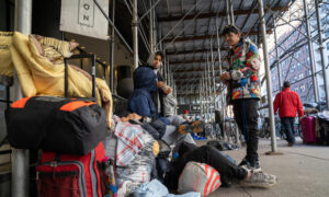 مهاجرون ينتظرون في أحد الشوارع بعد طردهم من أحد الفنادق في نيويورك (EFE / Ángel Colmenares)