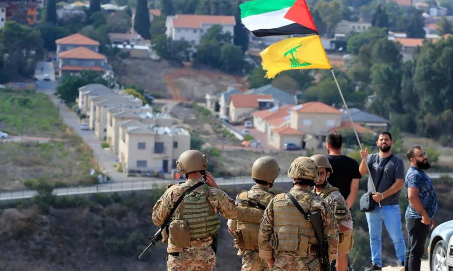 جنود لبنانيون ومواطنون يرفعون علمي حزب الله وفلسطين على الحدود مع الأراضي المحتلة 17 تشرين الأول 2023 (AFP)