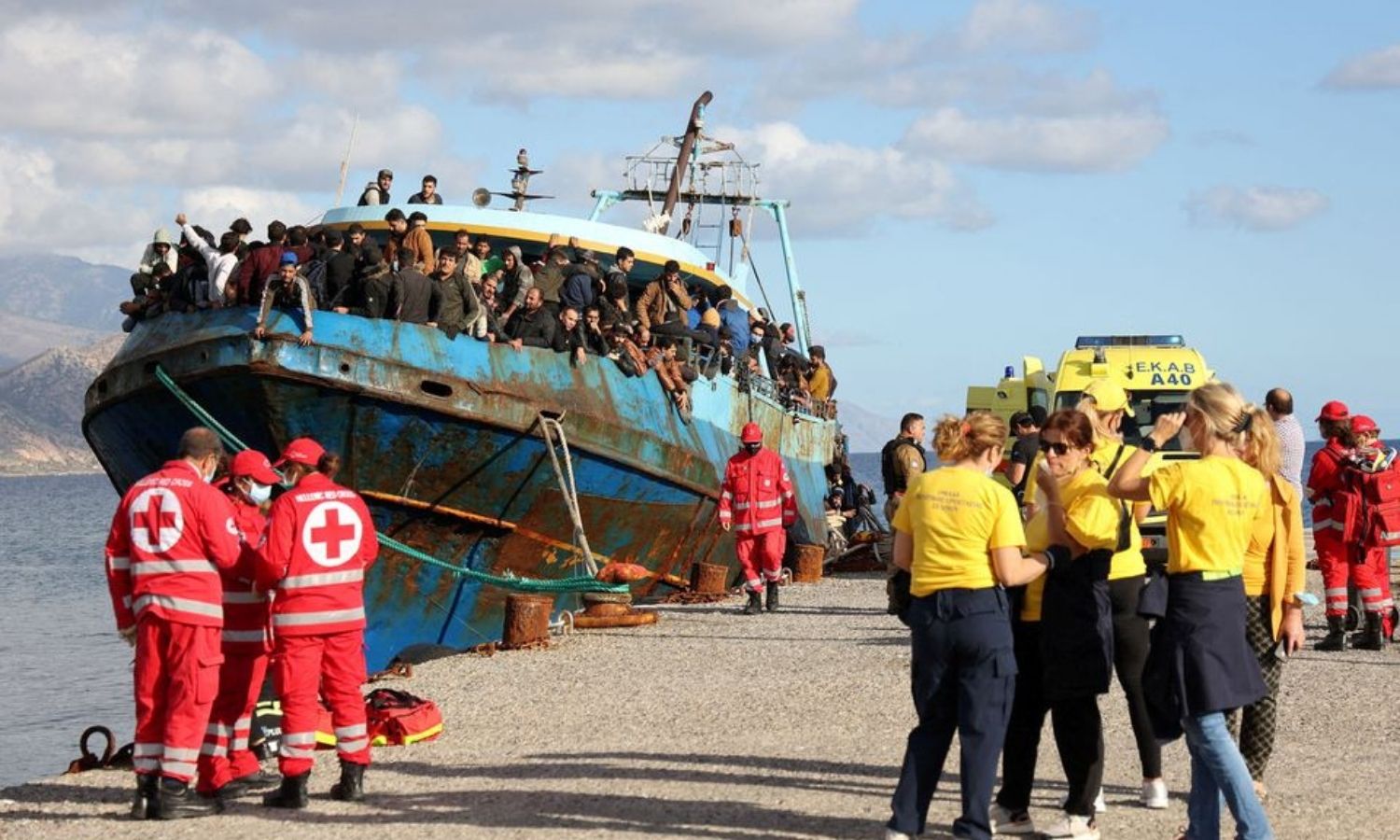 متطوعو الصليب الأحمر وطواقم الإنقاذ يقفون بجوار قارب صيد يحمل مهاجرين في ميناء باليوخورا، بعد عملية إنقاذ قبالة جزيرة كريت_22 من تشرين الثاني 2022 (REUTERS)