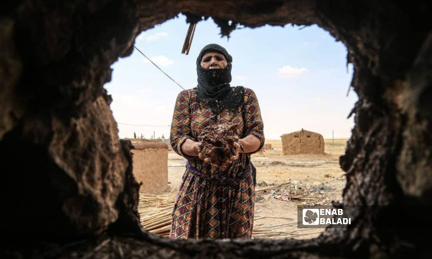 امرآة ريفية ترمم منزلها الطيني استعدادً لاستقبال فصل الشتاء- أيلول 2023 (عنب بلدي)