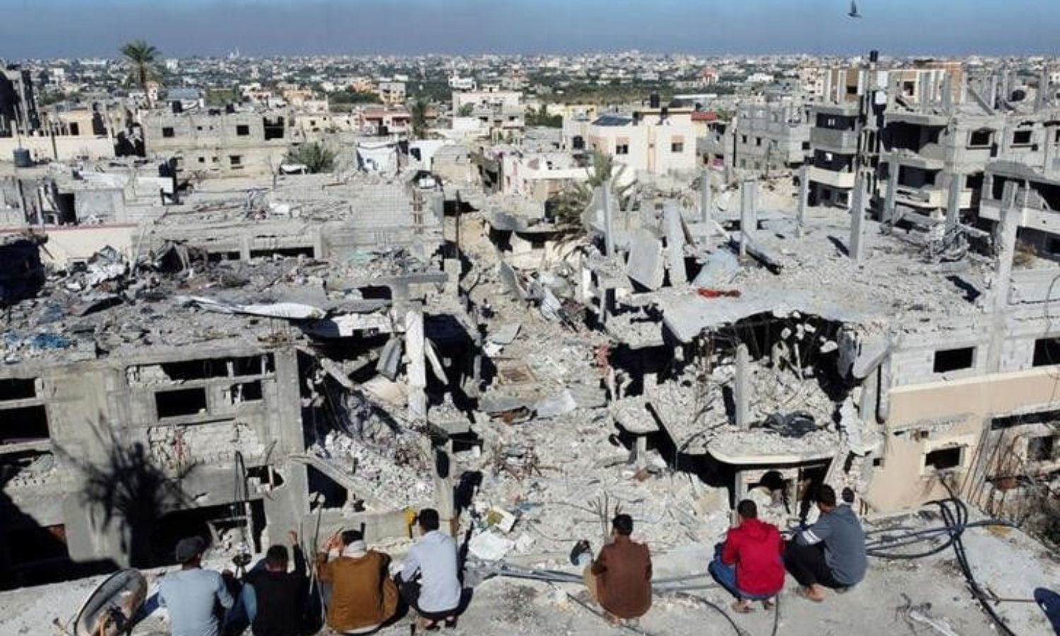 فلسطينيون ينظرون إلى المنازل التي دمرها القصف الإسرائيلي قبل الهدنة- 29 من تشرين الثاني 2023 (رويترز)