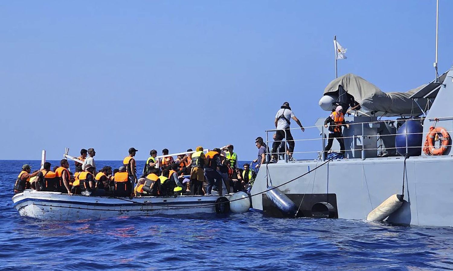 فريق الإنقاذ القبرصي وهو يساعد المهاجرين من قارب في البحر بالقرب من منتجع "بروتاراس" الساحلي الشرقي على الجانب الشرقي من جزيرة قبرص - آب 2023 (AP)