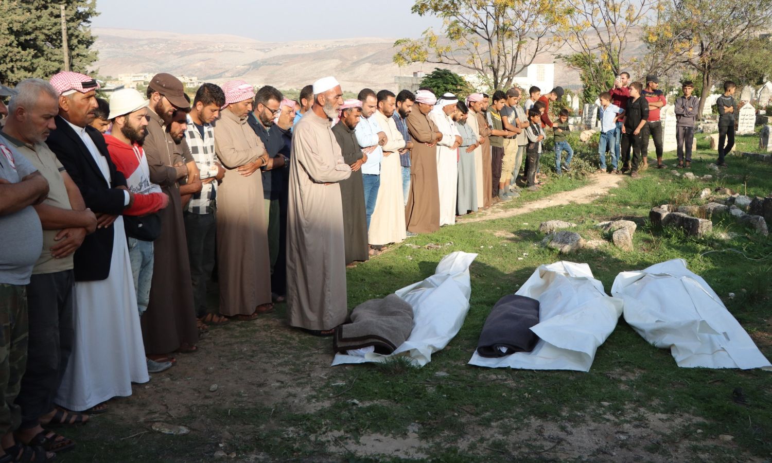 صلاة الجنازة على جثامين ضحايا إثر مجزرة نفذتها الطائرات الحربية الروسية على مخيم "أهل سراقب" في ريف إدلب الغربي - 24 من تشرين الأول 2023 (الدفاع المدني السوري)