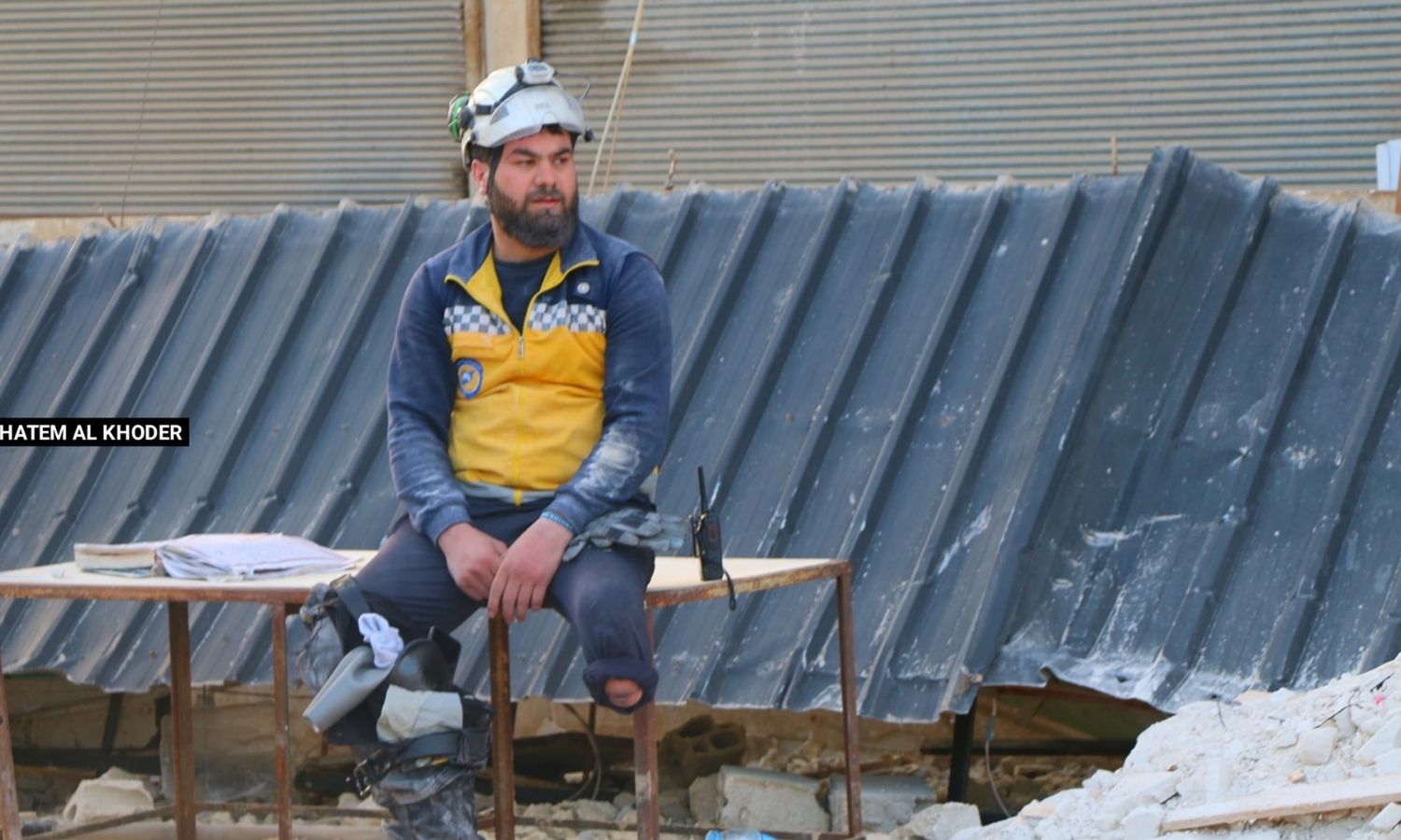 المتطوع في "الدفاع المدني السوري" حسن الطلفاح يجلس وبجانبه طرفه الاصطناعي للراحة بعد عمليات إنقاذ العالقين تحت الأنقاض إثر الزلزال بريف إدلب_12 من شباط 2023 (حاتم الخضر/ فيس بوك)