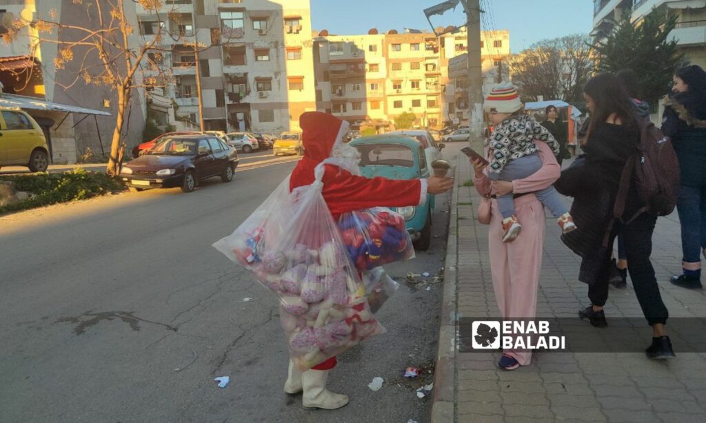 رجل بلباس "بابا نويل" يوزع الهدايا على الأطفال في مدينة اللاذقية – 21 من كانون الأول 2023 (عنب بلدي/ ليندا علي)