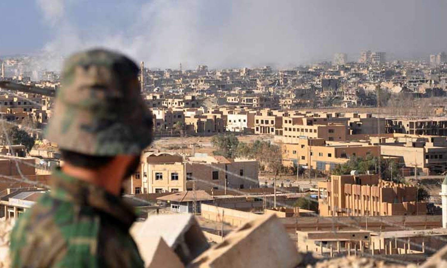 مقاتل من قوات النظام السوري يقف على الجبل المطل على مدينة دير الزور (AFP)