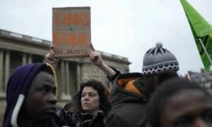 متظاهرون ينتظرون أمام المجلس الدستوري الفرنسي في باريس اعتراضًا على قانون الهجرة الجديد - 25 من كانون الثاني 2024 (AP)