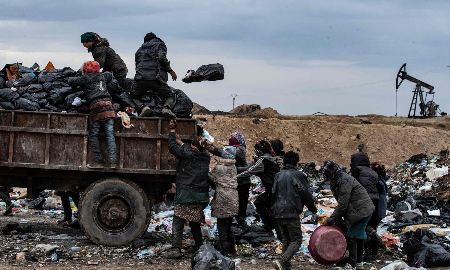 سوريون يبحثون في مكب للنفايات بالقرب من بئر نفطي بالقرب من مدينة المالكية شمال شرقي سوريا- 20 من كانون الثاني 2021 (فرانس برس)