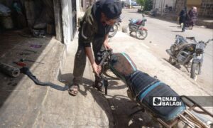 طفل يعمل على إصلاح دراجة نارية في مدينة طفس 27 من آيار 2023 (عنب بلدي/حليم محمد)

