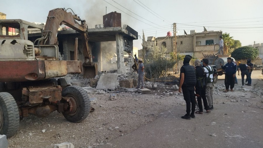 مقاتلون محليون في مدينة جاسم يحاصرون منزلًا كان بتحصن به القيادي في تنظيم “الدولة الإسلامية”، الملقب بـ"أبو عبد الرحمن العراقي"، خلال الحملة الأمنية في المدينة- 17 من تشرين الأول 2022 (تجمع أحرار حوران)