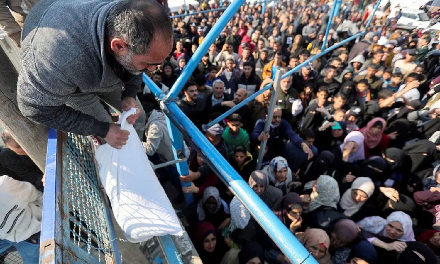 رجل فلسطيني يحمل كيسًا من الطحين والكثيرون ينتظرون استلامه خلال فترة الهدنة المؤقتة بين "حماس" وإسرائيل- 29 من تشرين الثاني 2023 (رويترز)